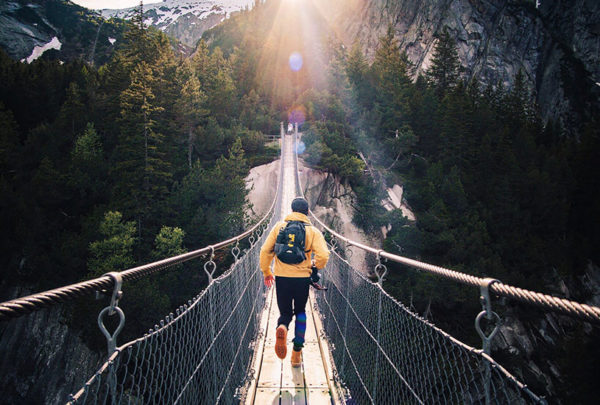 Person on a narrow bridge in the wilderness running in to the other side