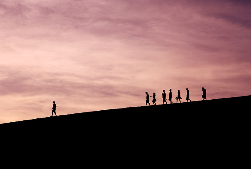 silhouette of one person walking while others follow