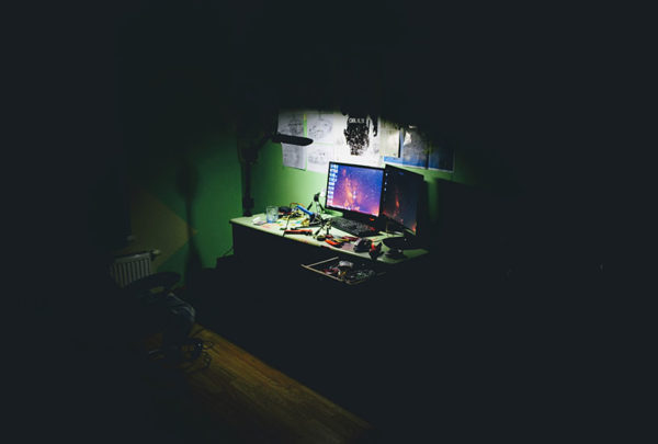 dark room with desk in the spotlight full of tools and a computer