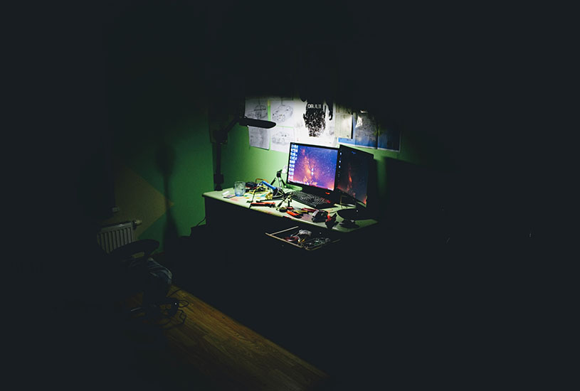 dark room with desk in the spotlight full of tools and a computer