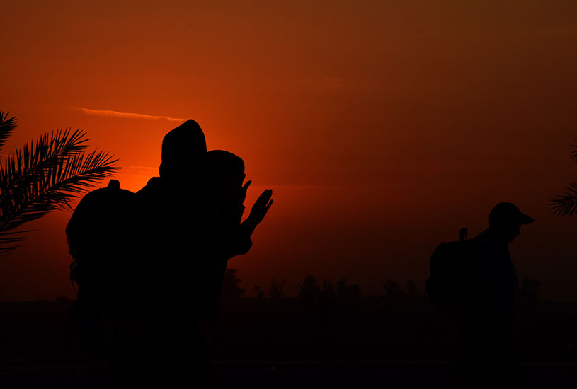 silhouette of people with bags travelling in the sunset