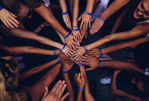 group of people putting their hands together of multiple colour
