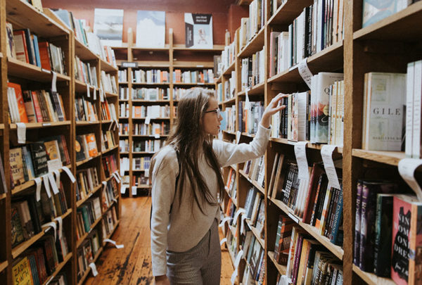 lady wearing glasses looking to find a book in the library