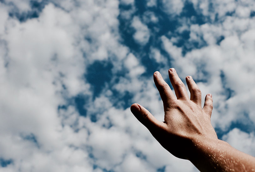 hand reaching to a cloudy sky