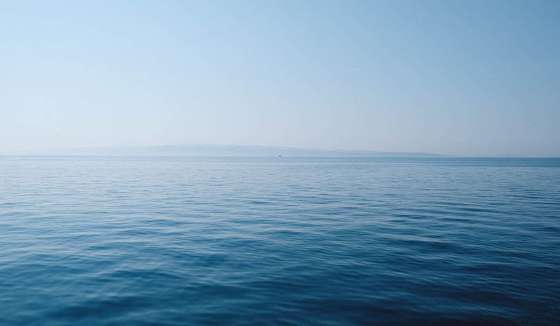blue sea with land in the distant horizon