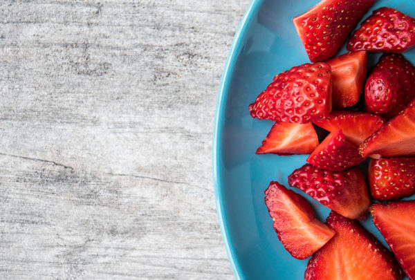 Blue plate with sliced strawberries on table