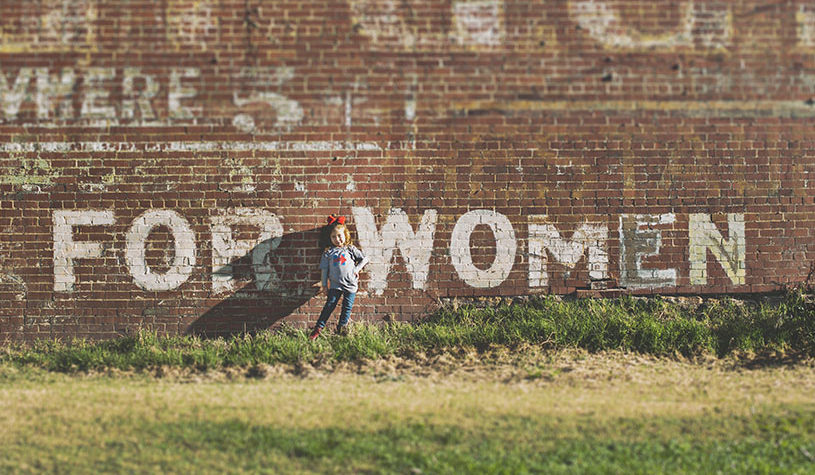 girl standing in front of wall saying for women