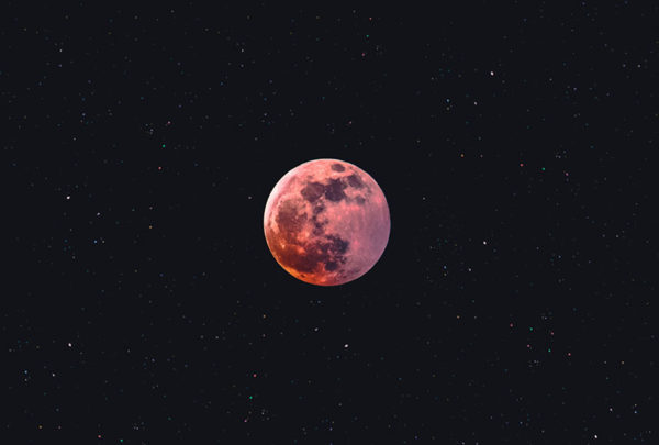 A red moon set against the black, night sky.