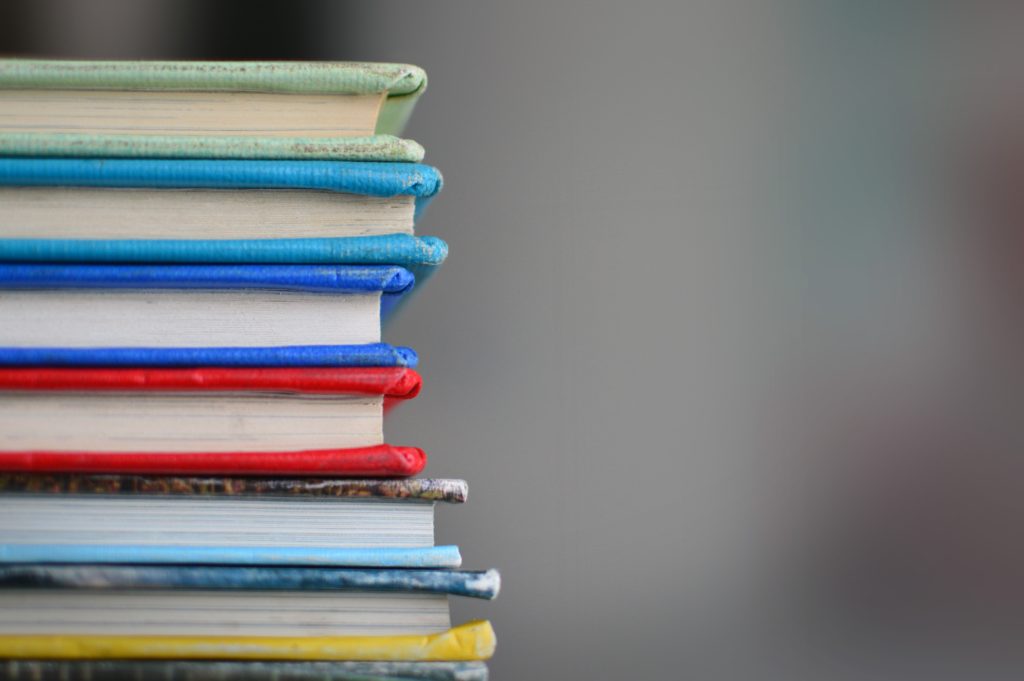 Seven books of varying colours stacked on top of each other.