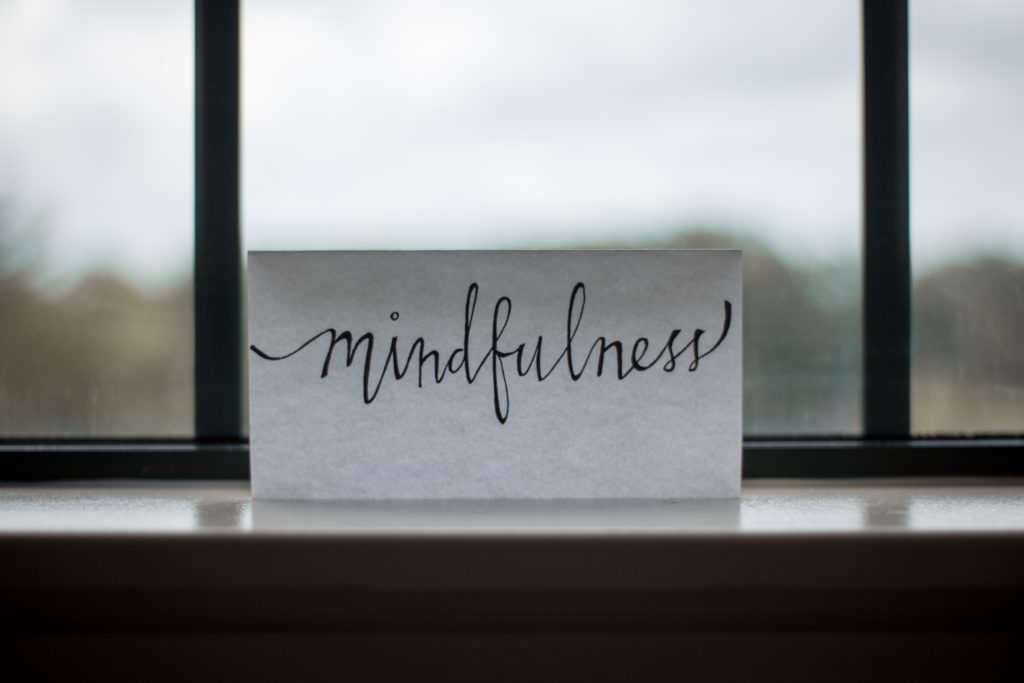 A card with mindfulness printed on it set against a window.