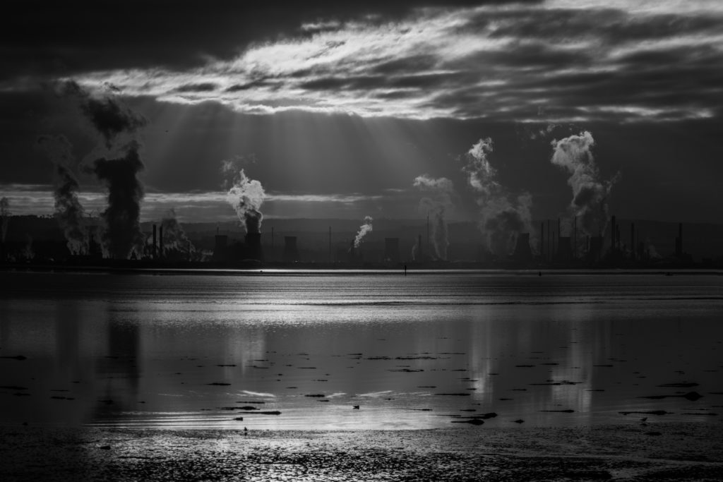 A black and white image of the Grangemouth oil refinery set against the Scottish landscape.