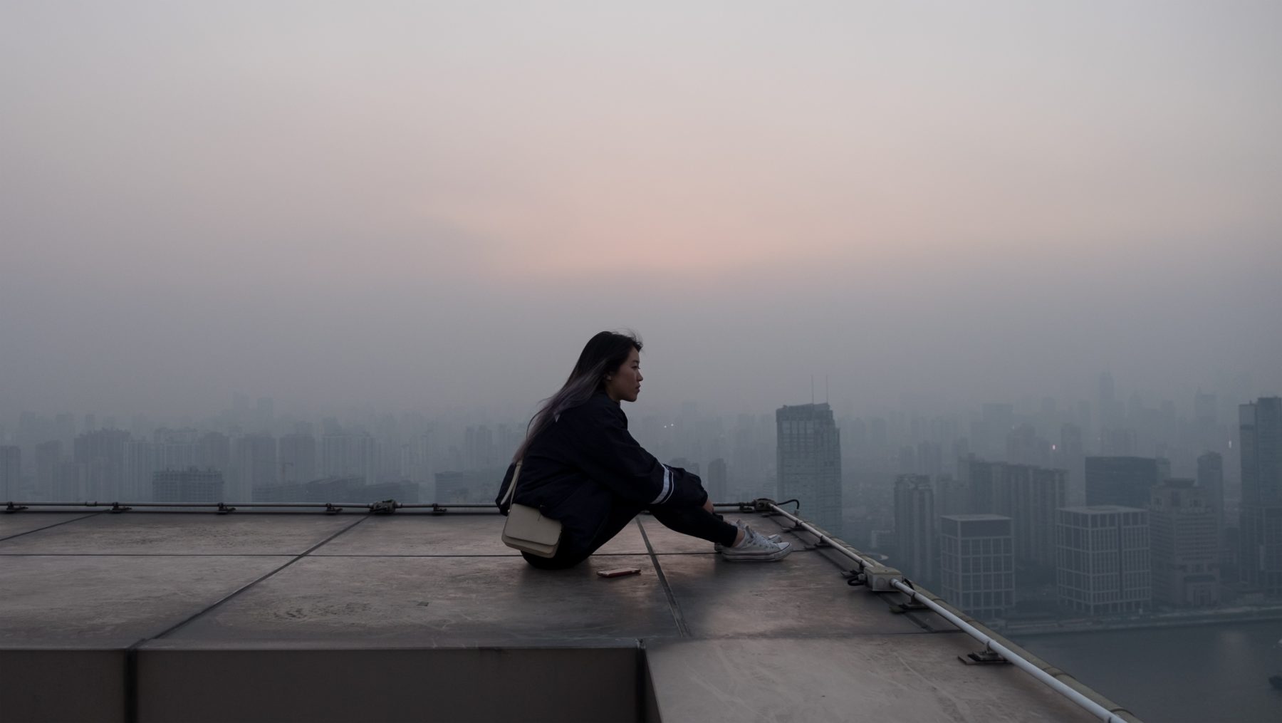 A young woman sitting on top of a building in Beijing.