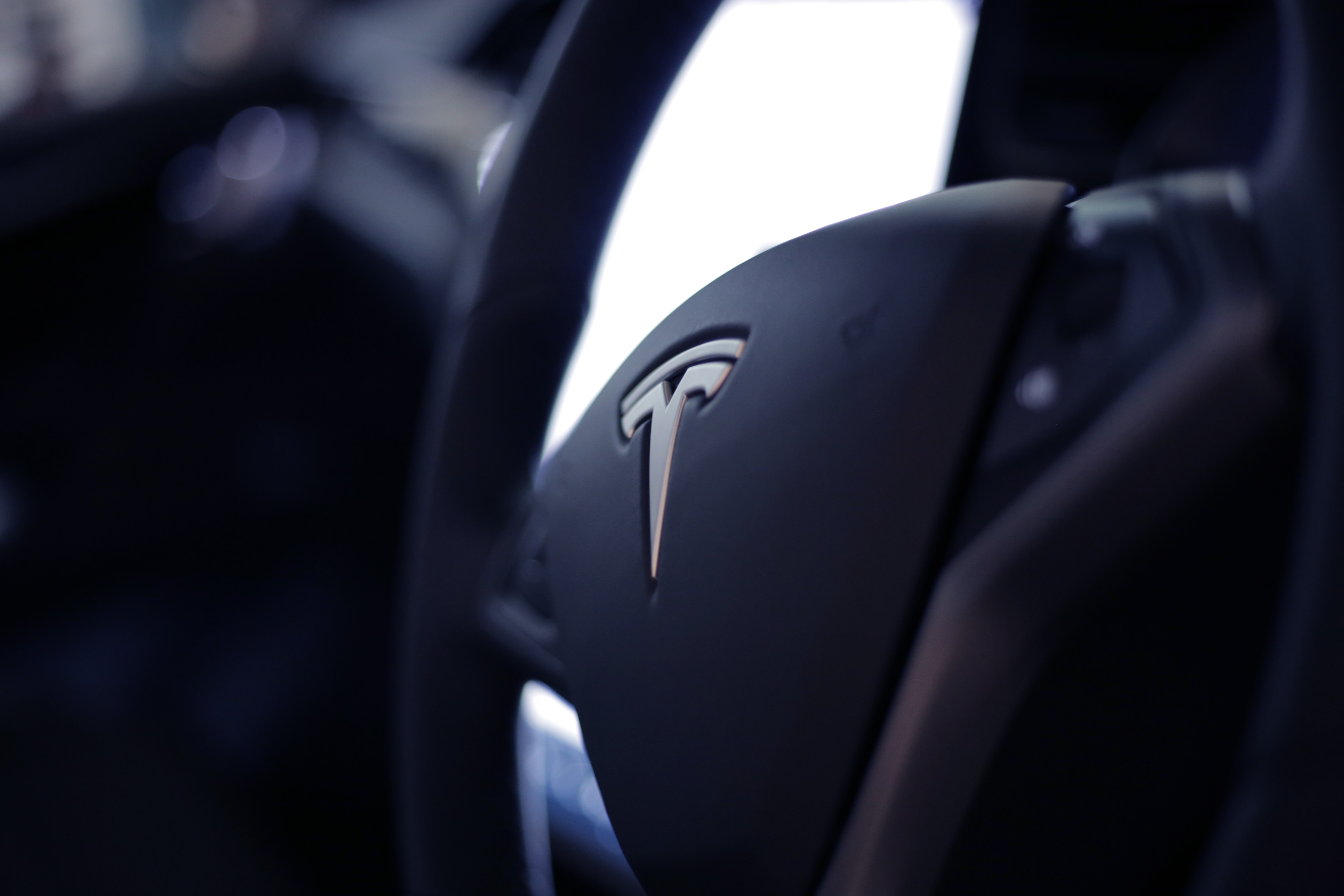 The Tesla logo on the steering wheel of one the cars.