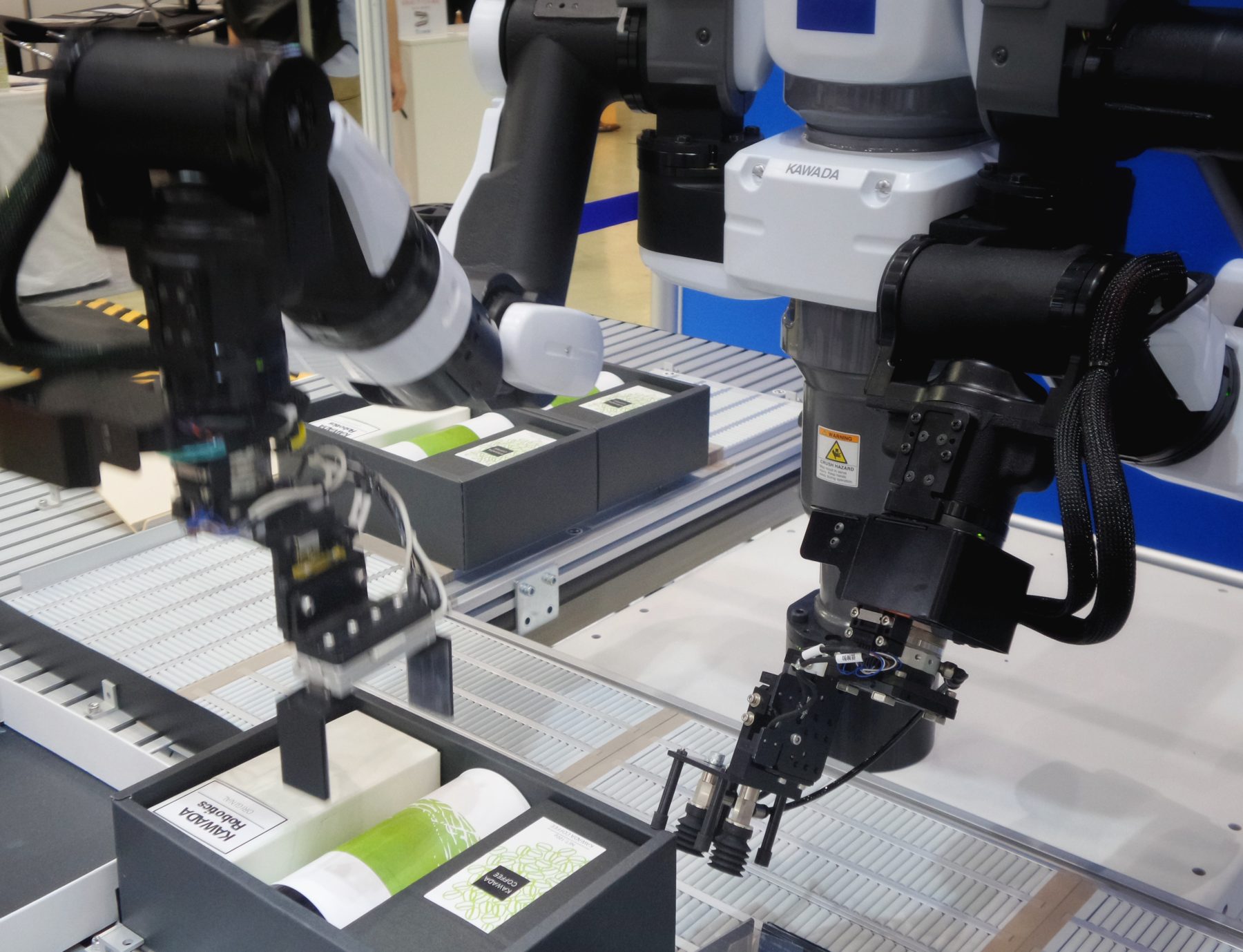 Two robotic arms packaging products in a factory.