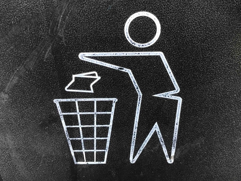 A diagram of a man throwing his trash in the trash can.