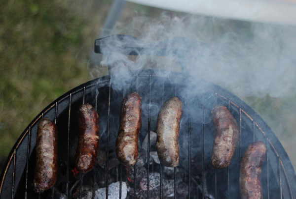 Sausages cooking on a barbeque.