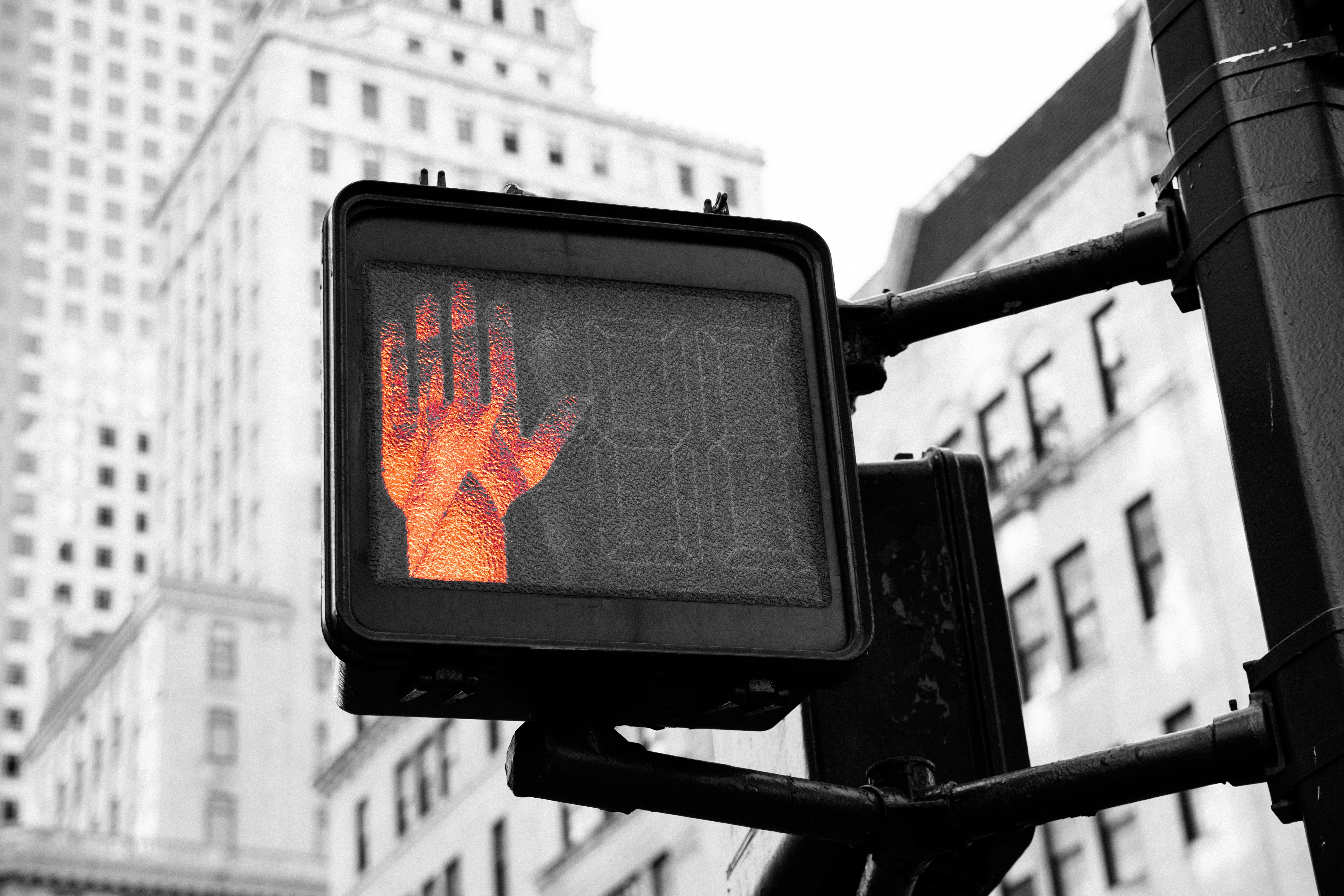 A red hand signalling stop at a pedestrian crossing.