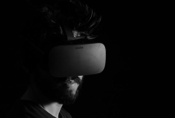 Portrait of a man wearing virtual reality goggles against a black background.
