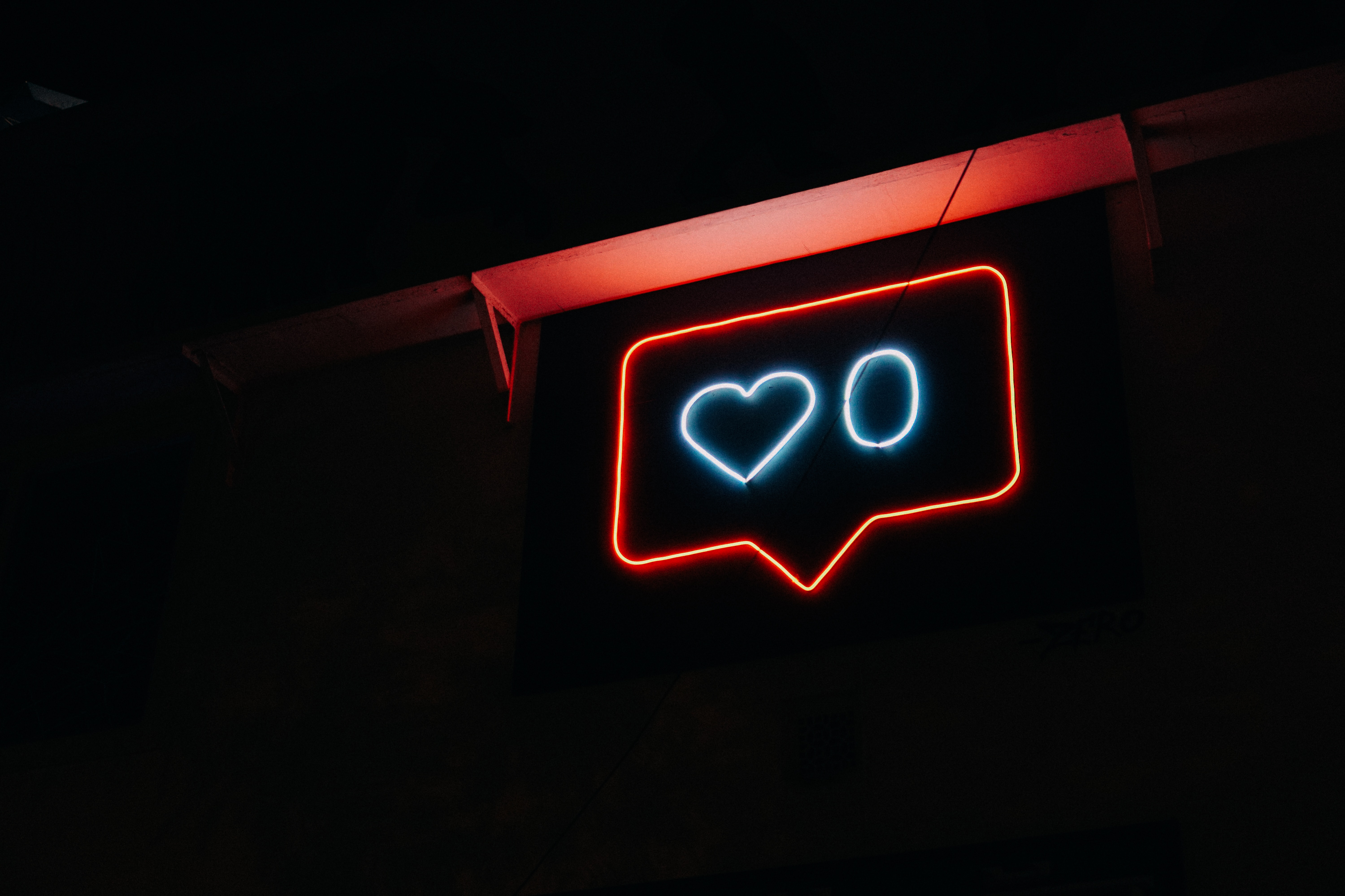 A neon sign in the design of the Instagram like feature, with a love heart and a zero inside it.