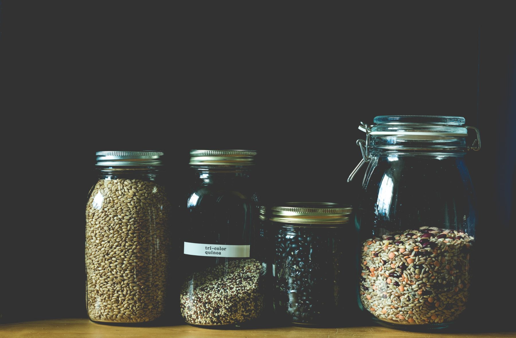Four jars filled with quinoa and other super grains.