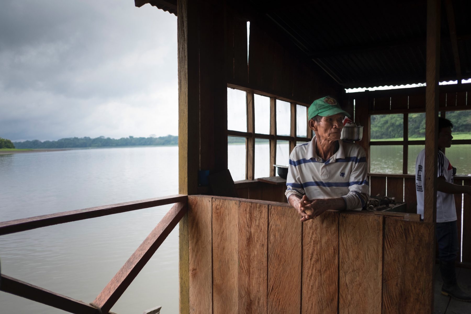 An Colombian local wearing a green hat sitting by the Amazon river.