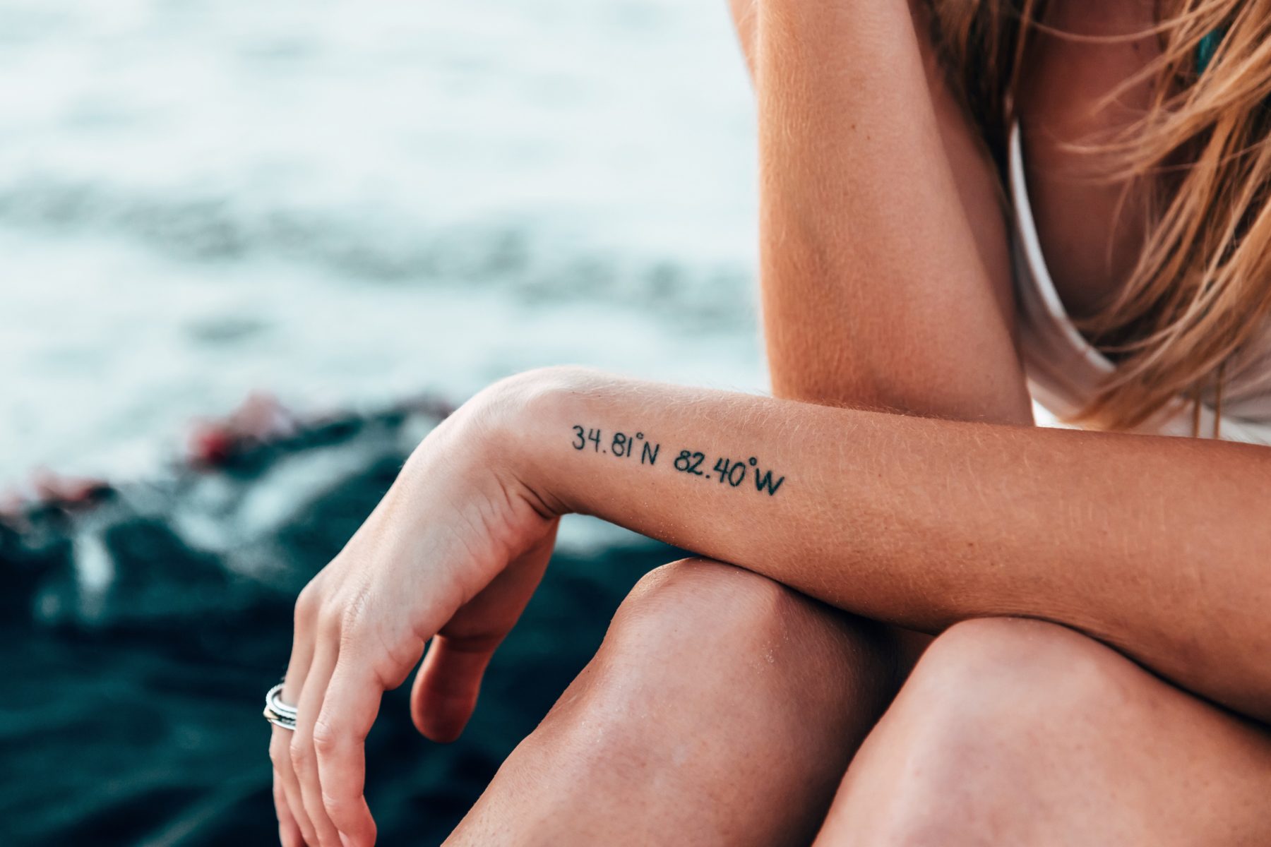 A girl with coordinates tattooed on her forearm.