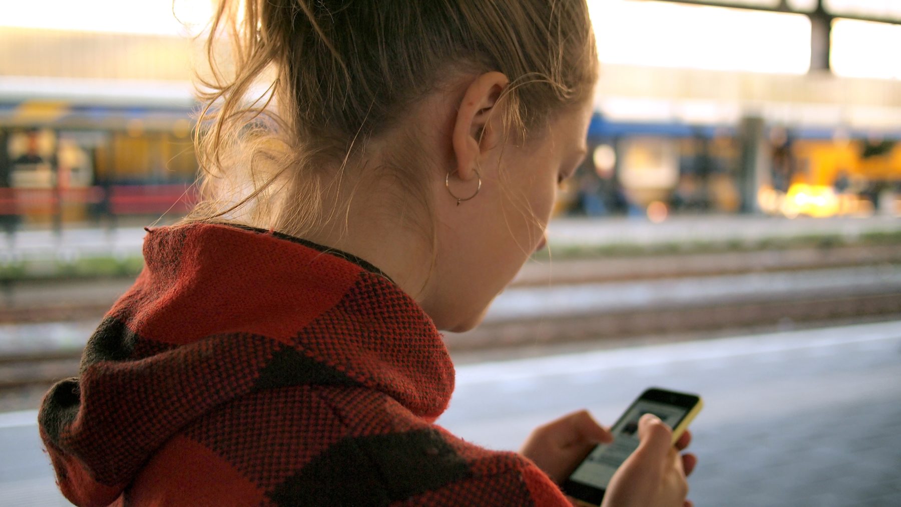 A young women using her smartphone at a train station.
