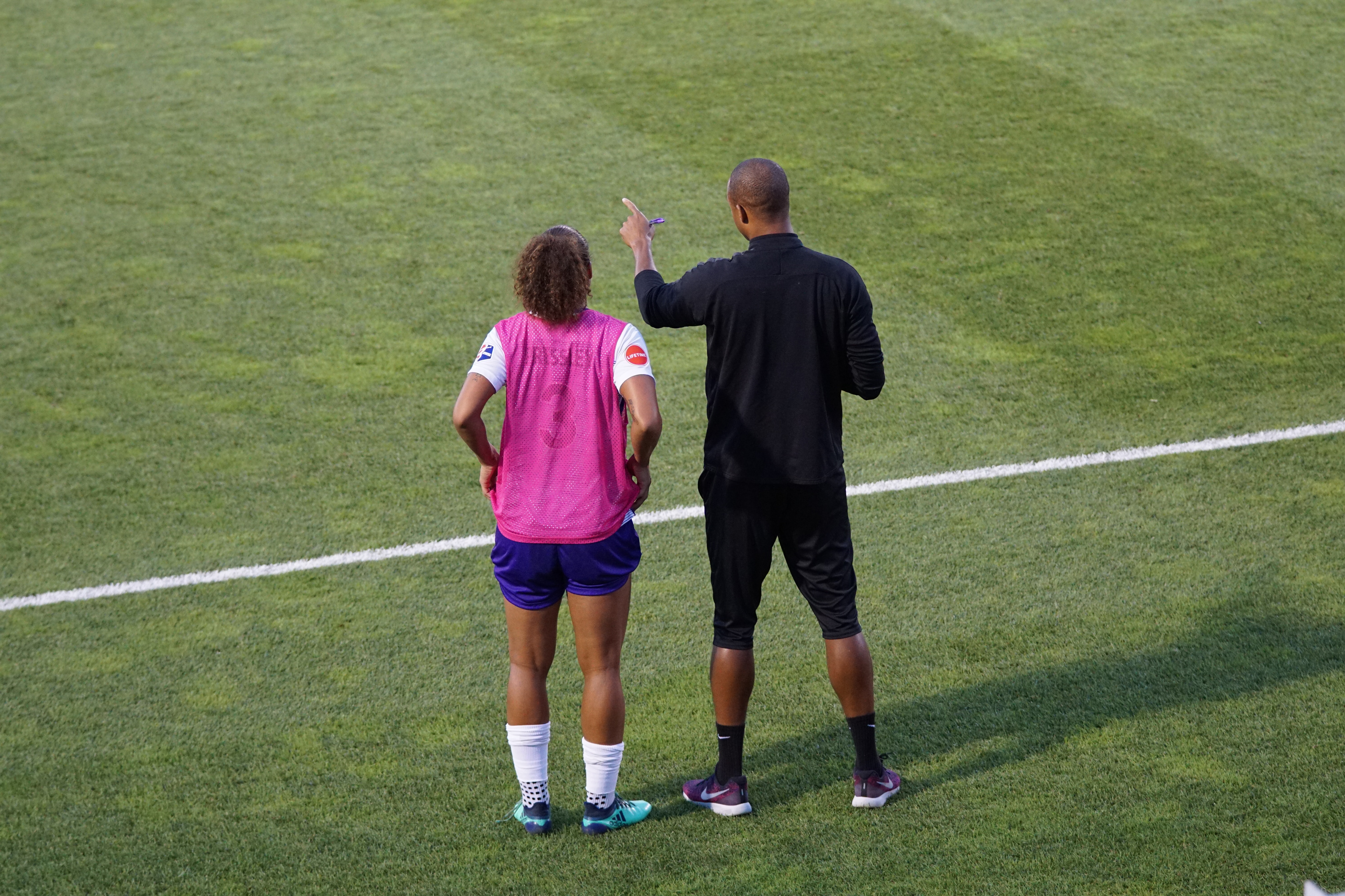 A soccer coach giving instructions to a substitute player on the sidelines.
