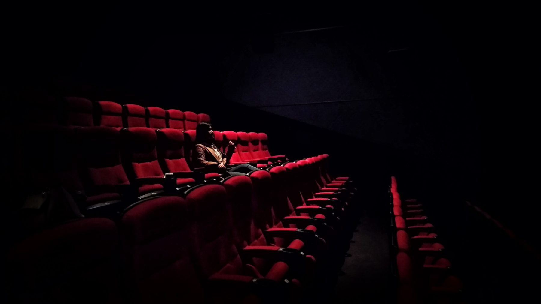 A young woman sitting alone in a theatre.