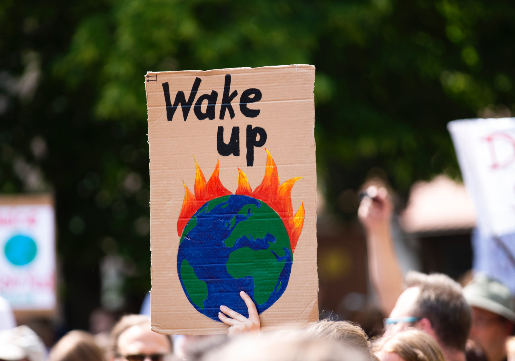 A person at a protest holding a placard with the words "wake up' on it.