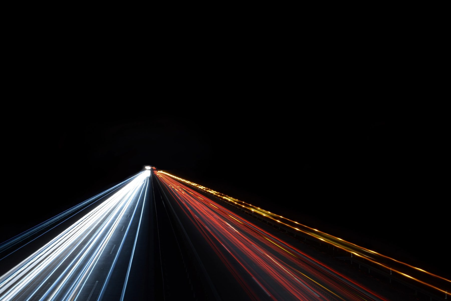 A long exposure of a car driving by on a road at night.