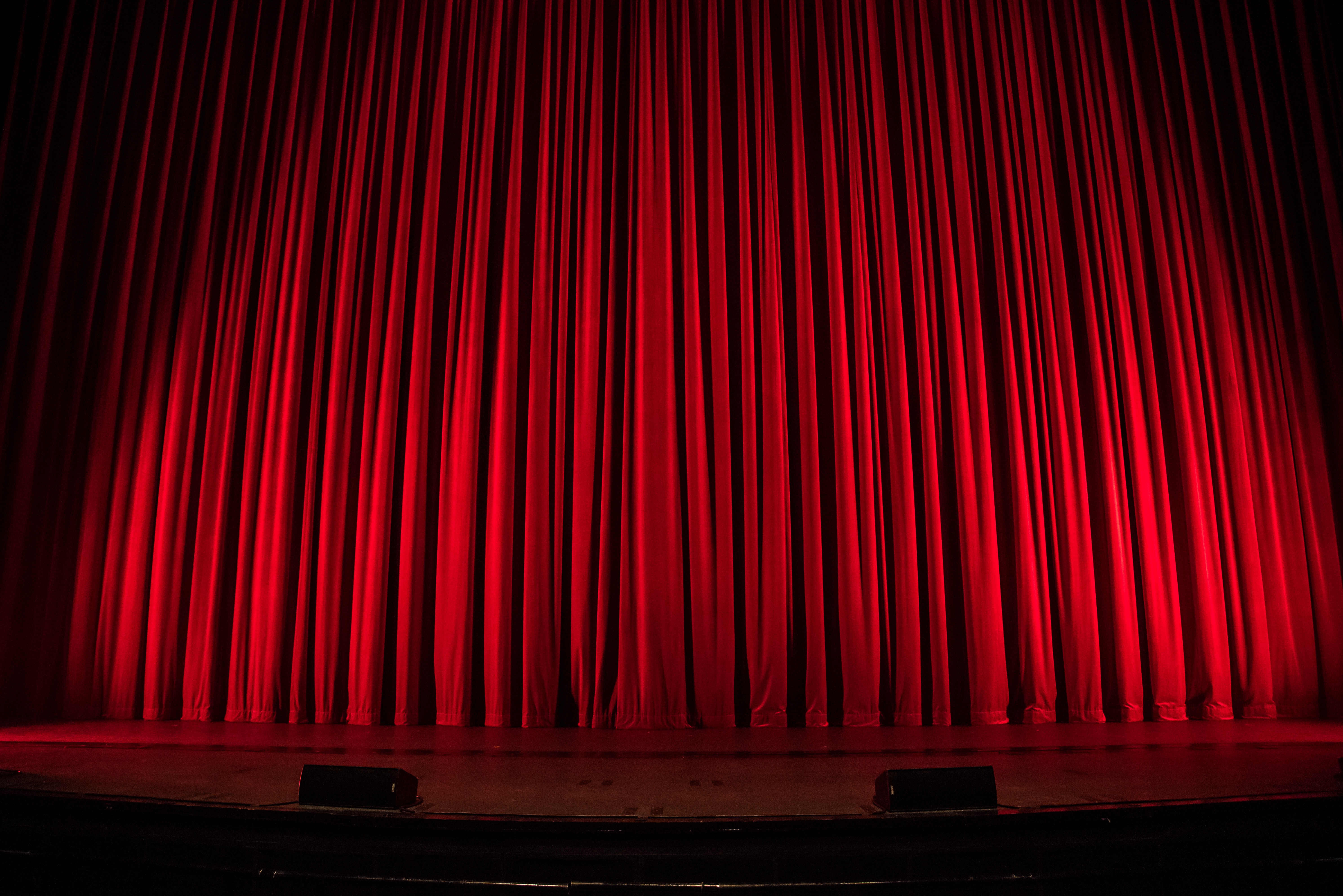 Red curtains closed on a theatre stage.