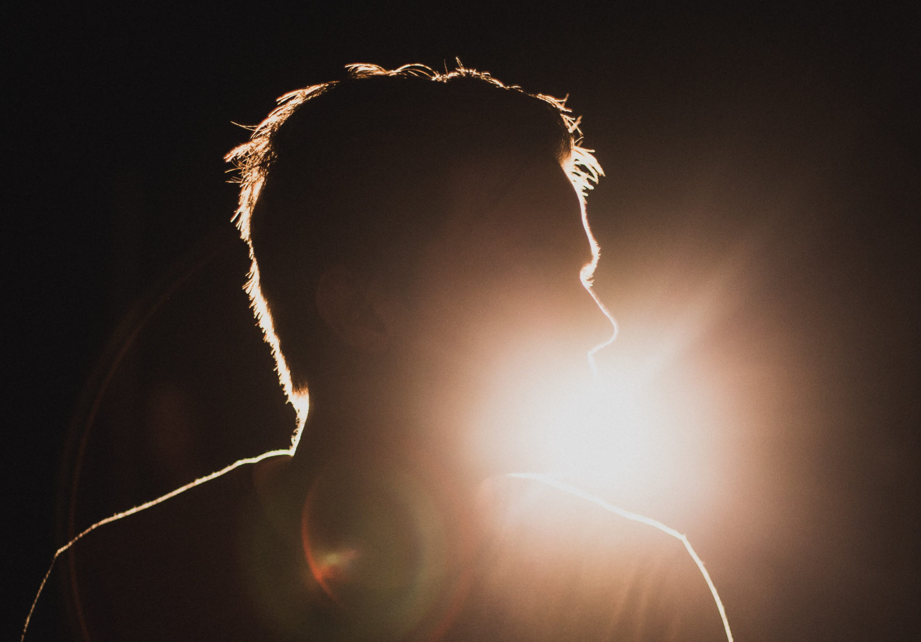 A silhouette of a man being lit up by a light in the background.