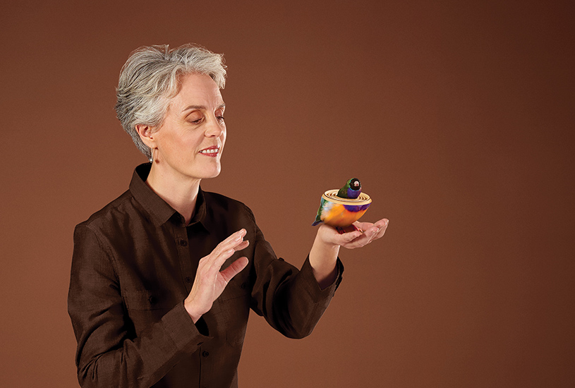 Professor Kate Buchanan holding a model bird in the palm of her hand.