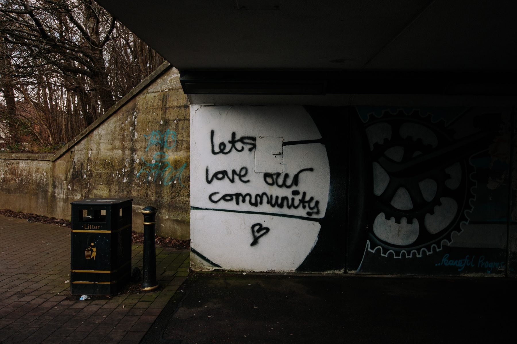 A piece of graffiti in an underpass that says "let's love our community."