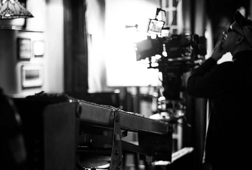 A camera operator operating a video camera in black and white.