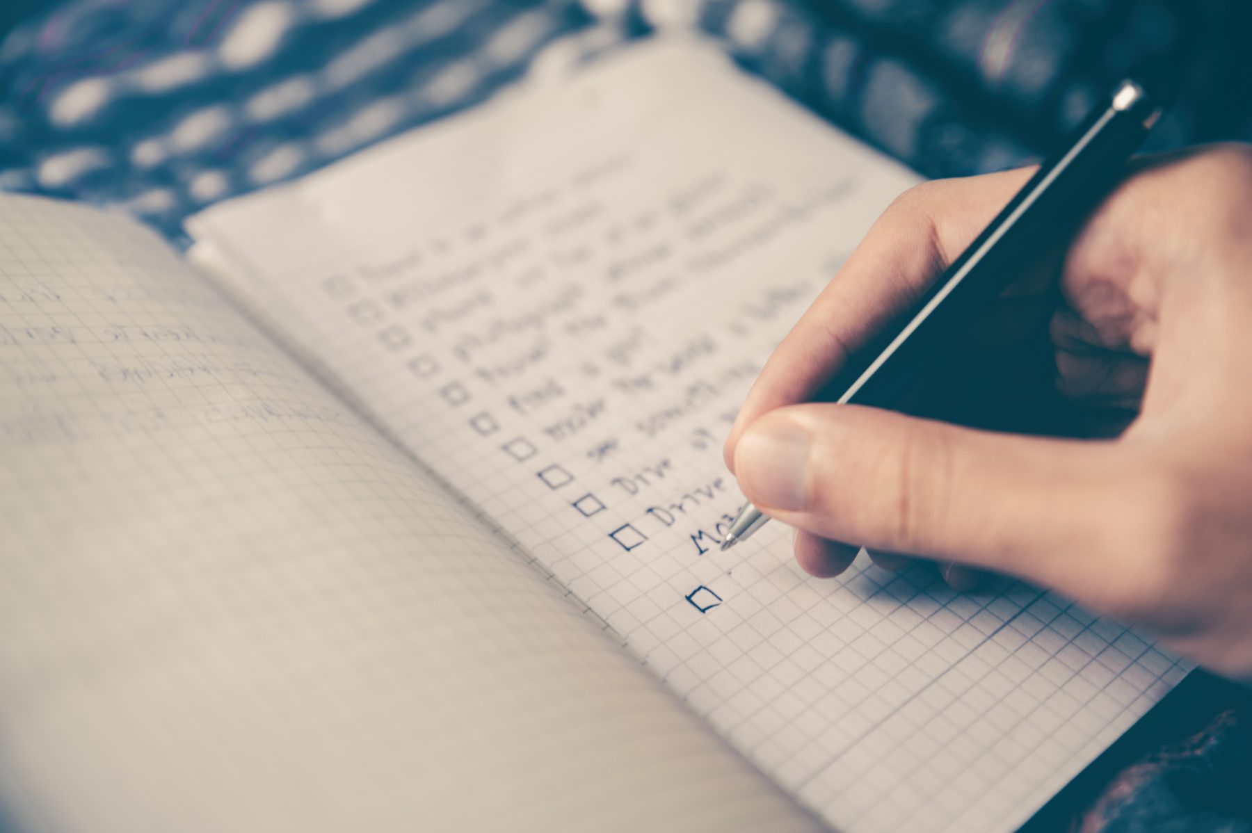 A person writing down a checklist in a notebook.