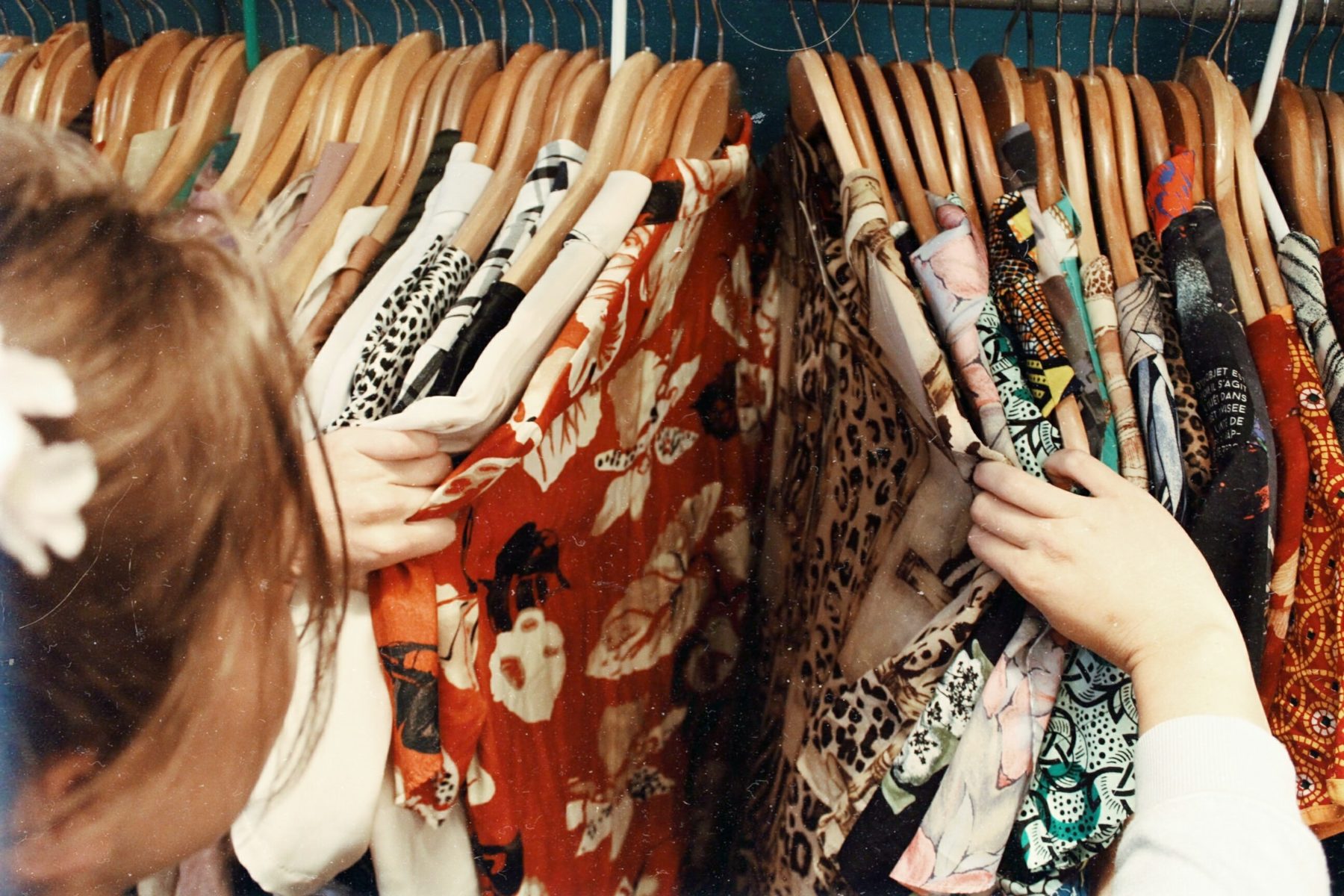 A young woman browsing through a rack of clothes.