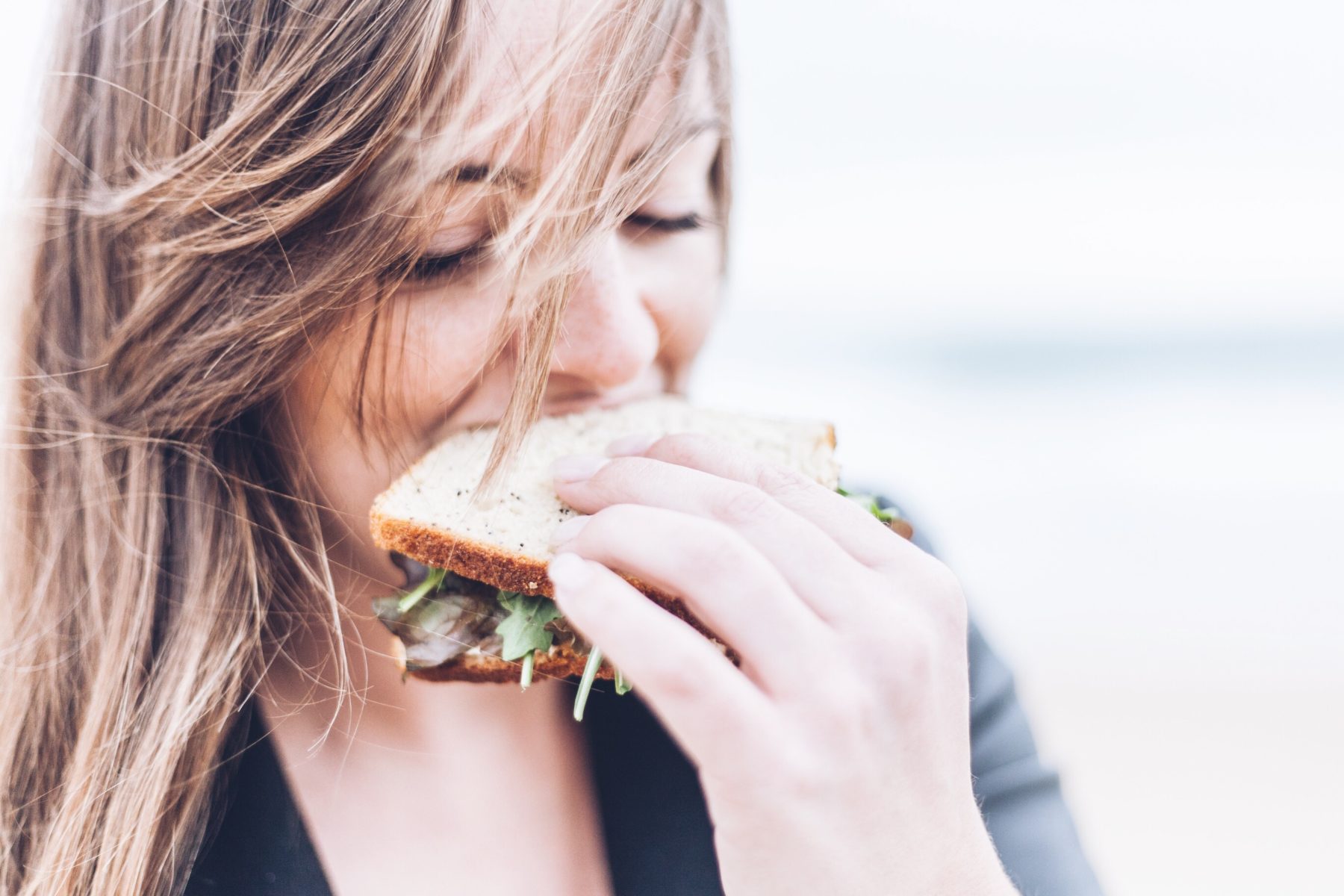 A young woman eating a sandwich.