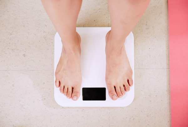 A close up image of a person's feet standing on a weighing machine.