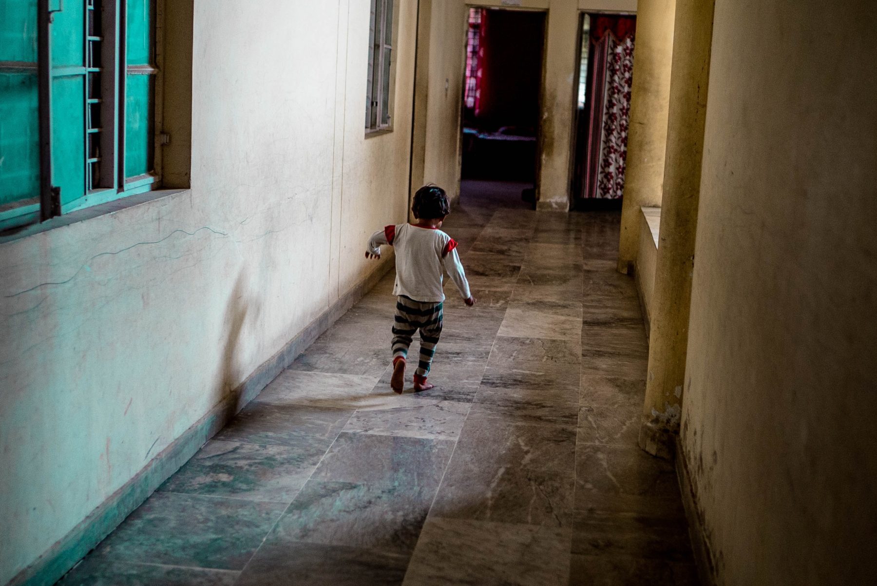 A young child wandering down a corridor.