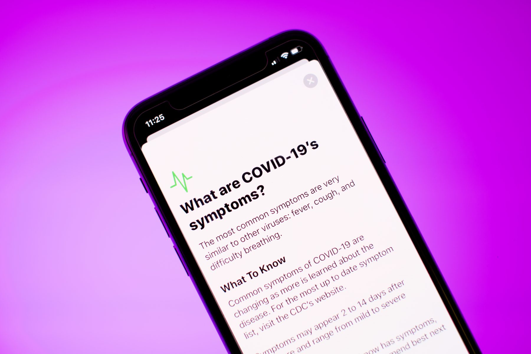 Image of a smartphone displaying a webpage of COVID-19 symptoms 