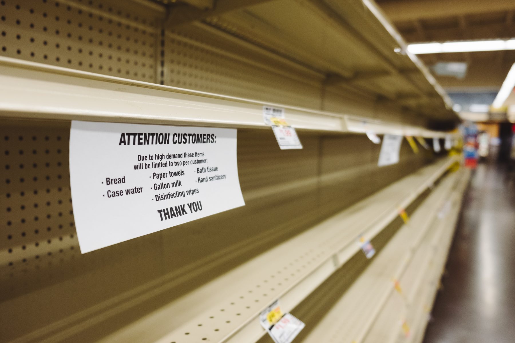 Image of empty supermarket shelves with note about limited supplies of toilet paper 