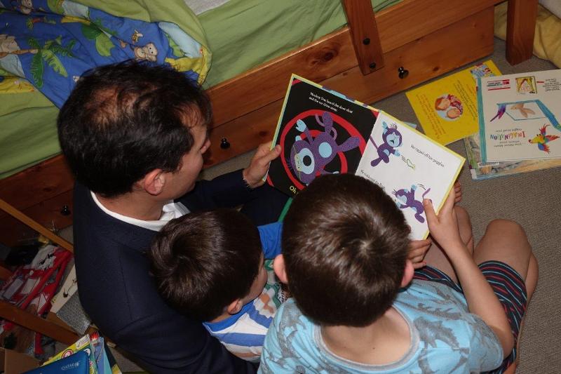 Image of parent and children reading a book