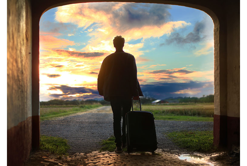 Image of a person walking through an archway with suitcase