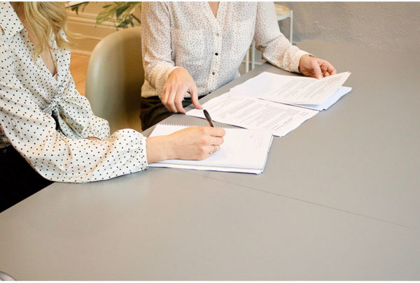 Image of two people at a desk with paperwork