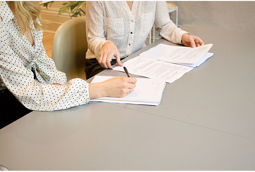 Image of two people at a desk with paperwork
